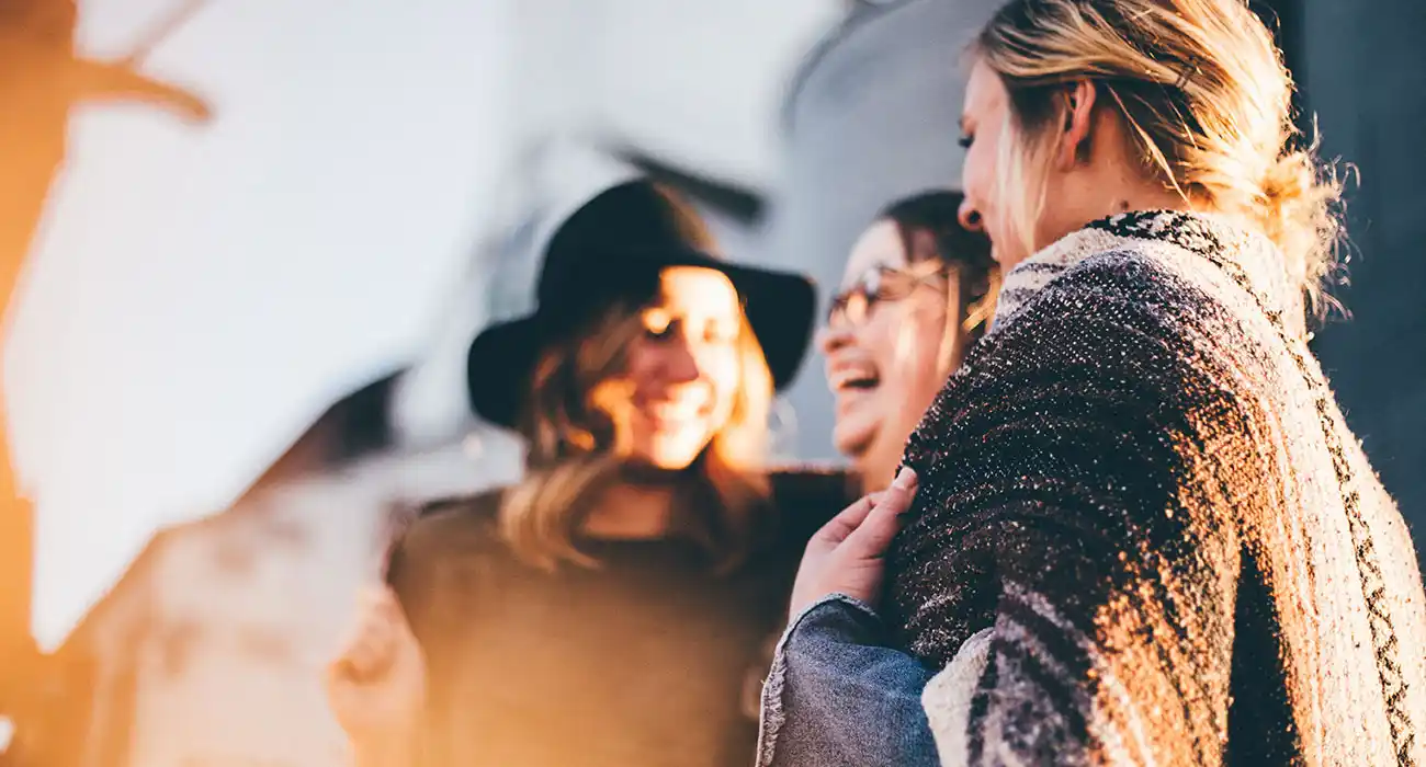 Drei Freundinnen lachen gemeinsam im Freien.